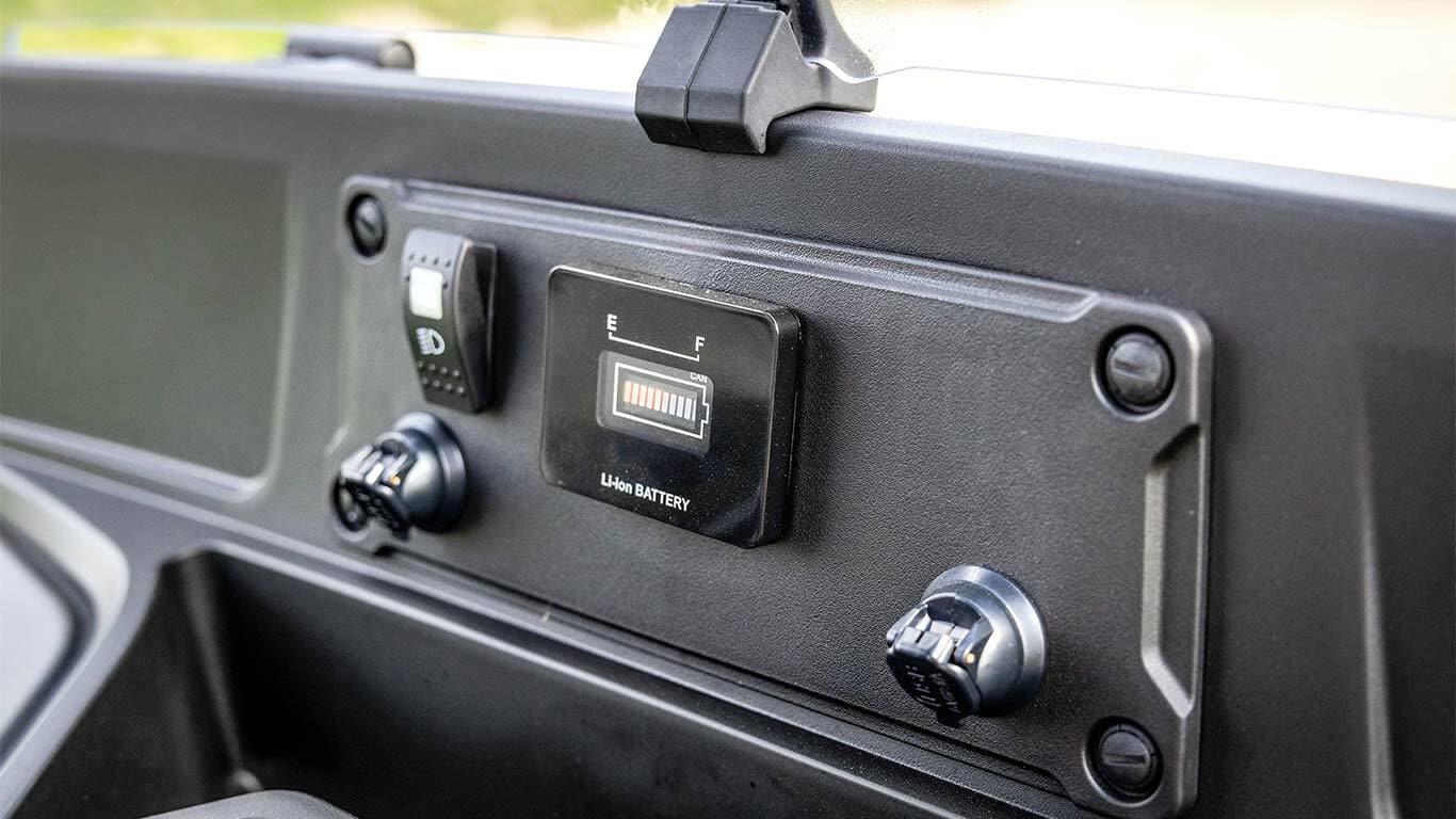 לוח מחוונים של דגם John Deere Gator GS חשמלי עם מחוון הטעינה של המצבר וחיבורי החשמל.